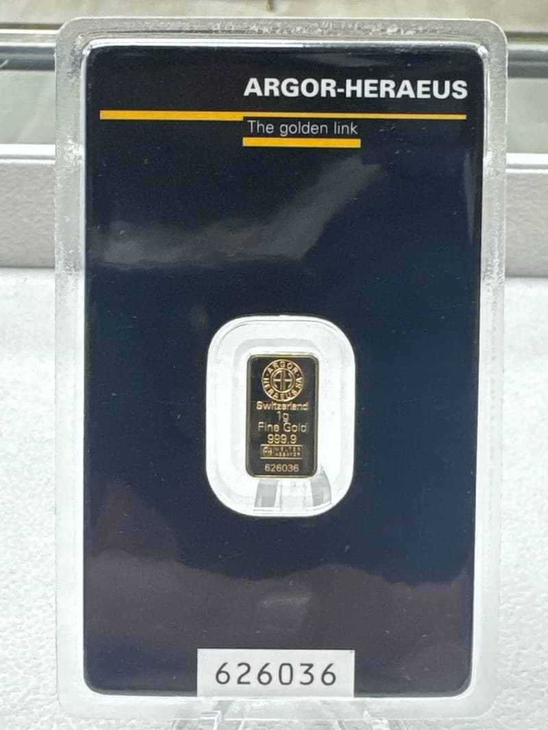 A 1 gram Argor-Heraeus fine gold bar, stamped 999.9 and serial 626036, sealed in its dark Argor-Heraeus assay card with the matching serial number